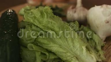 蔬菜在厨房的木盘上旋转的宏观镜头，包括洋葱、大蒜、莴苣、笋
